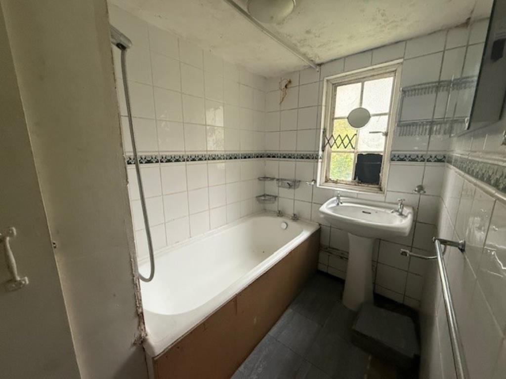 Lot: 115 - A PAIR OF THATCHED COTTAGES IN NEED OF IMPROVEMENT - 48 Abbey Street tiled bathroom with bath and sink